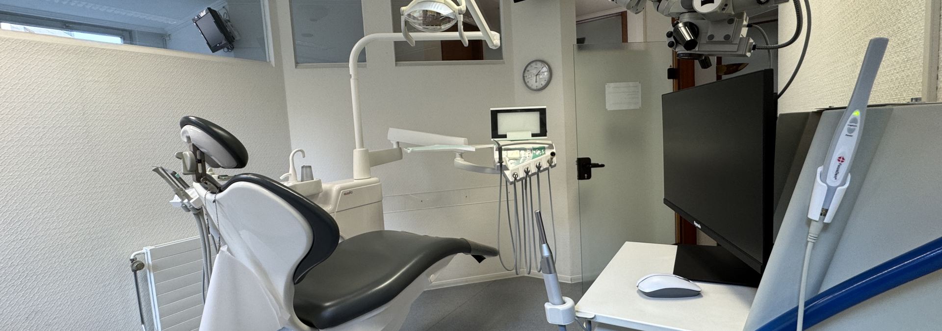 Behandlungszimmer beim Zahnarzt in Nürnberg Dr. Thomas Schulz (links steht ein Behandlungsstuhl, rechts steht ein Mikroskop für eine bessere und schmerzfreiere Versorgung bei z.B. Wurzelkanalbehandlungen